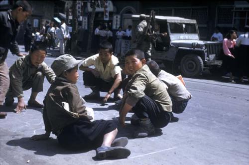 Boys playing in street, Jeep in background