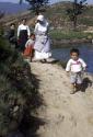 Women and children walking along path next to water