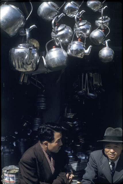 Men sitting beneath hanging tea kettles