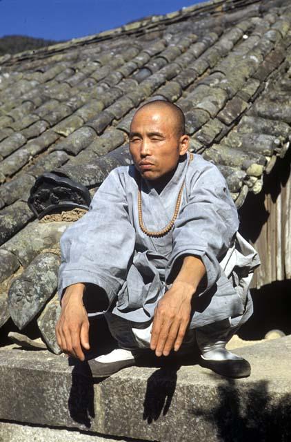 Buddhist monk sitting on the roof of a house