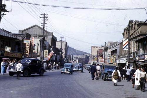 People and cars in busy street of a town