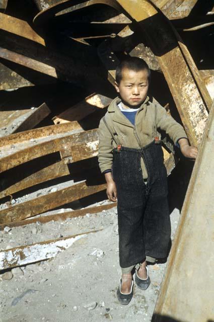 Boy by pile of wooden planks