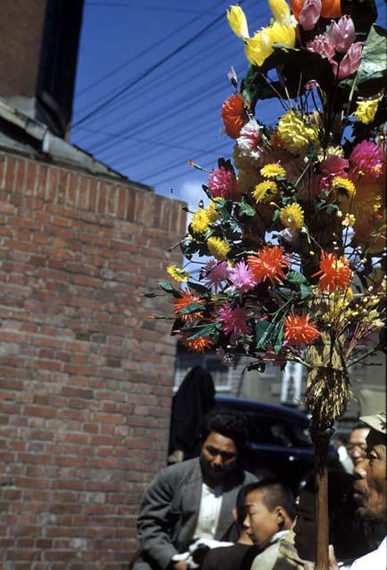 People standing by pole with bouquet of flowers hanging on it