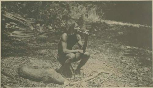 Chocó Indian man smoking pipe beside a dead pig