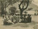 Group gathered with goods beneath tree