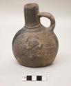 Spouted and strap-handled jar with molded figure and circle with crescent