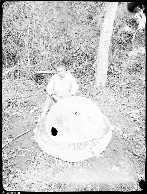 Man sitting next to a circular carved stone