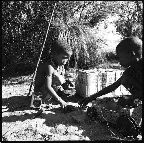 Two children playing with a toy car made from an expedition file box and film reels