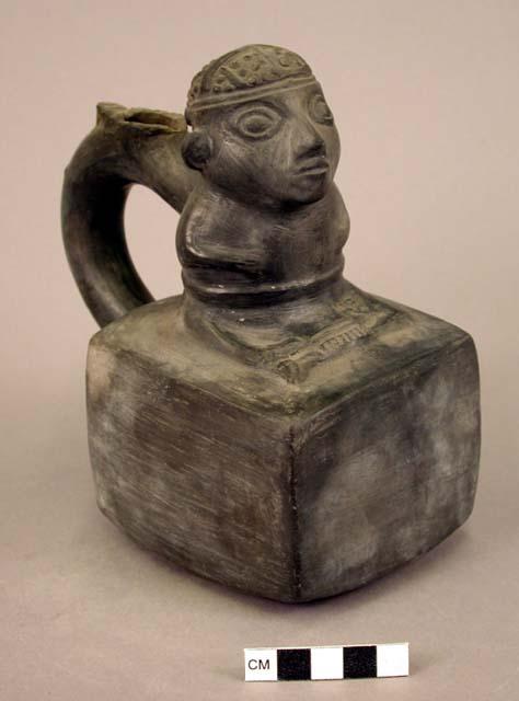 Ceramic bottle, stirrup spout, human effigy sitting cross legged on square base