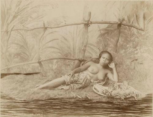 "Fruit Seller" -- A studio staged scene of Samoan woman reclining on the ground beside a basket of fruit