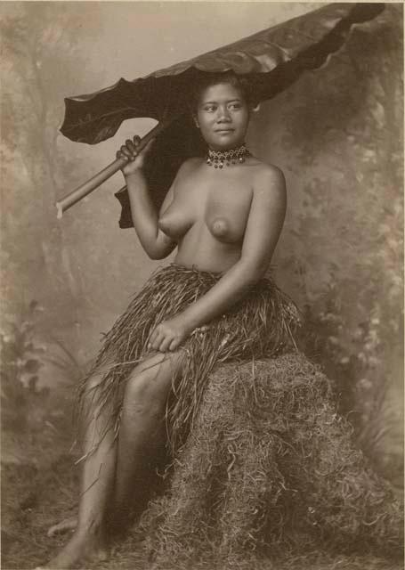 Samoan girl holding large leaf, studio portrait