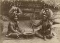 Two Samoan men wearing headdresses and seated on a mat