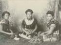 Three Samoan women seated in front of backdrop, wearing formal tops and jewelry
