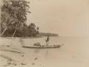 Beach scene, man standing in a canoe