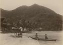 Beach scene - a man and woman in canoe launching off, and a group of children seated on a shored canoe