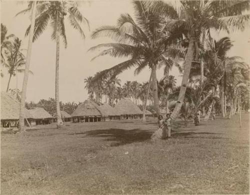 Young girls stand at a tree with houses in background