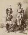 Two young Samoan men in studio portrait, one wears tuiga (headdress), both hold swords