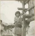 Little boy. Part of house construction and its bamboo walls may be seen