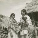 Native with one of his two wives. Her capeblouse is made from red bandana handkerchiefs
