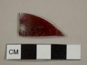 Colorless, curved glass shard with red glass layer underneath