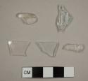 Colorless curved glass fragments, one possibly from a lamp chimney, two with molded designs and letters