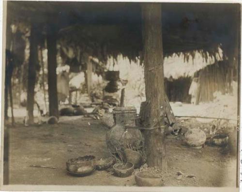 Bowls on ground near post of hut