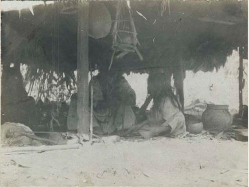 Man and child seated under hut