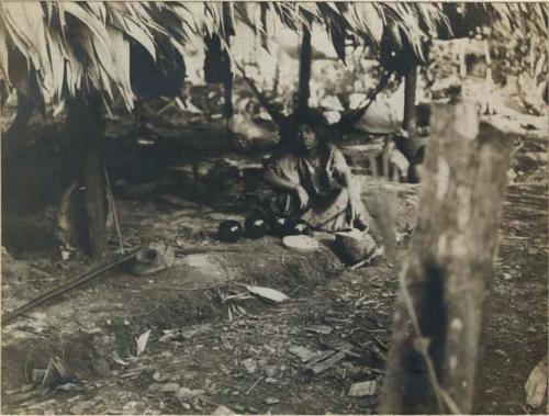Woman seated beneath hut