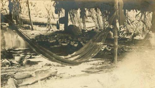 Hammock hanging in hut, pottery in the background