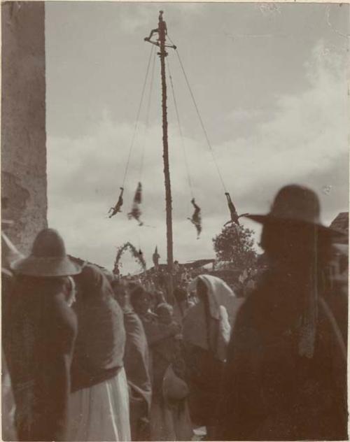 Men swinging on the pole of the Volador, one playing the fife and another a small drum