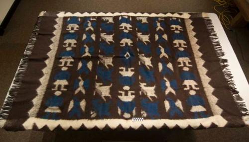 Blanket, brown with white and blue anthropomorphic figures, birds, and horses