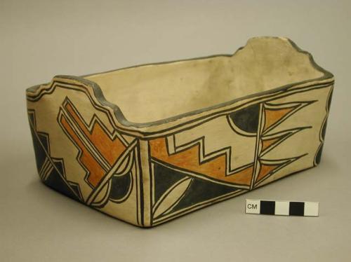 Rectangular pottery vessel. Flat bottomed, cream slip with orange and black