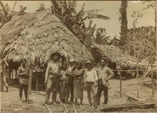 Group standing with huts in background