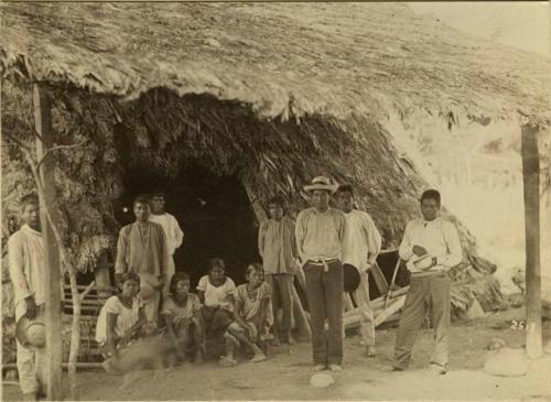 Group portrait under the overhang of a thatched house