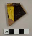 Staffordshire-type slipware rim sherd to a shallow bowl with a crimped rim
