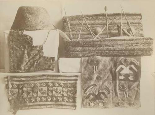 Woven fabrics of various patterns, Woman's work basket with contents (needles, yarn), and a cap