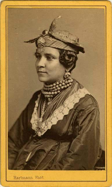 Woman, seated with hat and jewelry