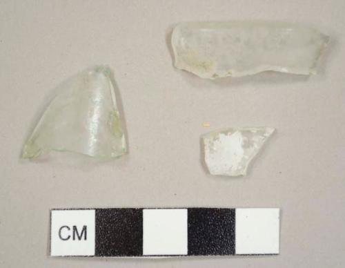 Colorless and aqua curved glass fragments, including one rim fragment to a possible jar