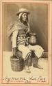 Studio portrait of man sitting, with ceramic vessel and basket