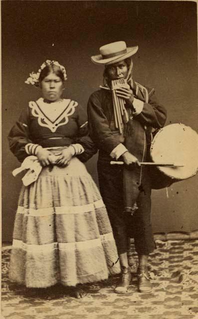 Studio portrait of woman, and man with drum and pan-pipe