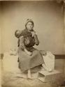 Studio portrait of woman with child in sling on back