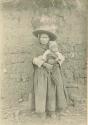 Woman standing with baby in front of a wall