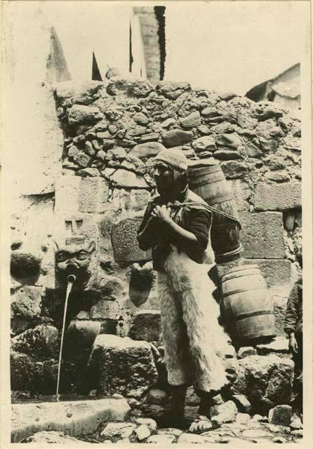 Man carrying barrels in front of fountain