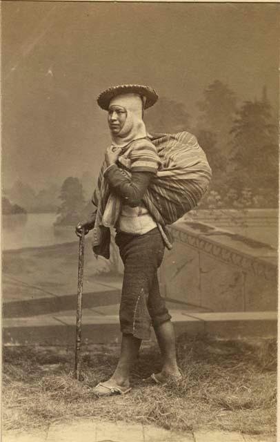 Studio portrait of person carrying large bundle on back