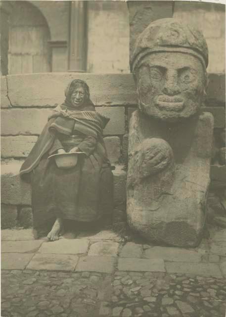 Woman sitting next to large carved stone figure