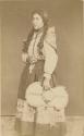 Studio portrait of woman standing and holding a hat