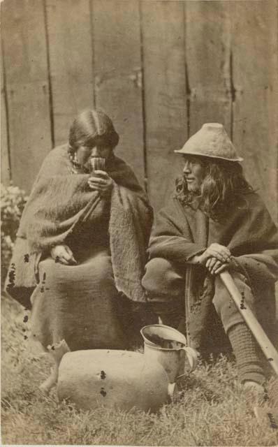 Woman and man sitting in front of a fence