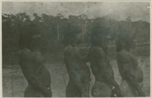 Four men standing next to body of water