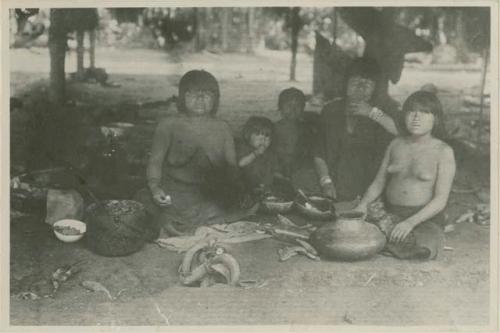 Three women and two children sitting with vessels and food