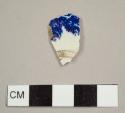 Blue transfer printed pearlware sherd with broken circular bit, possibly a footring, and perforation